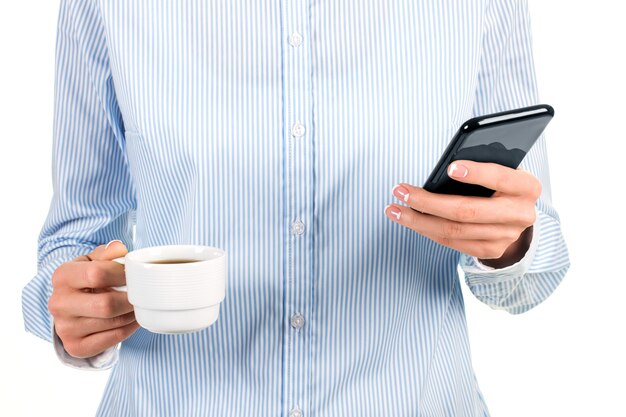 Xícara de chá feminina e celular. Senhora segurando o smartphone e a xícara. Lendo novas notícias no trabalho. Fico feliz que ele esteja totalmente carregado.