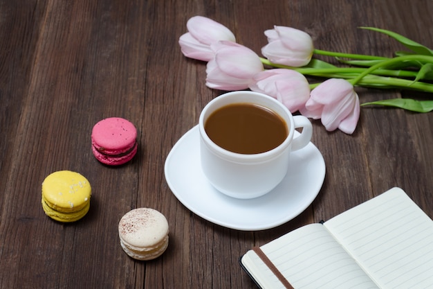 Xícara de chá, macarons, tulipas cor de rosa e notebook