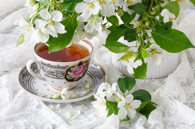 Xícara de chá na mesa de madeira e flor de maçã. Conceito de hora do chá. Xícara de chá de café da manhã servido com flores.