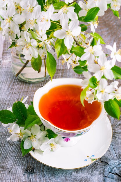 Xícara de chá na mesa de madeira e flor de maçã