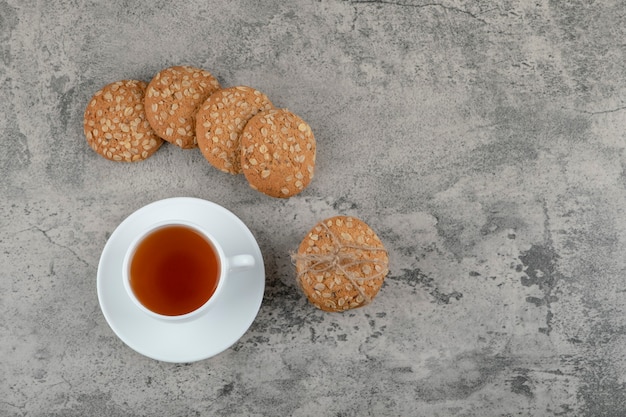 Xícara de chá preto com deliciosos biscoitos de aveia na pedra.