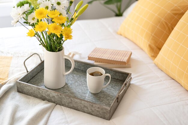 Xícara de chá quente e flores em uma bandeja no quarto