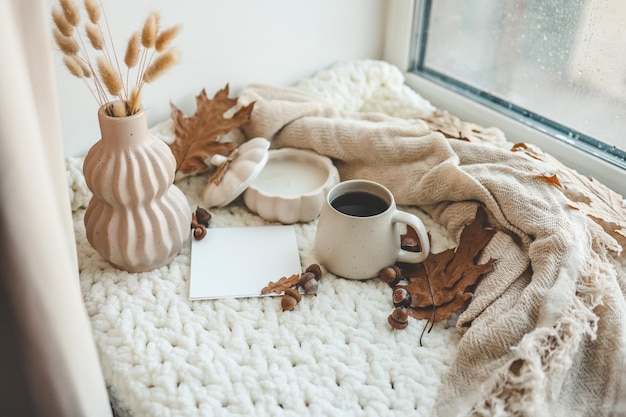 xícara de chá vela plaid e folhas no interior da casa de outono