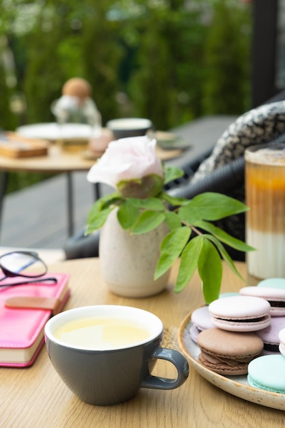 Xícara de chá verde com macarons de pastelaria de cores pastel em uma mesa de madeira