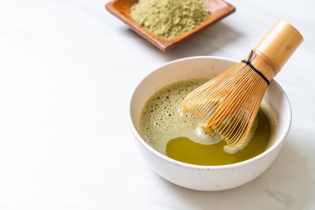 xícara de chá verde matcha quente com pó de chá verde e bata