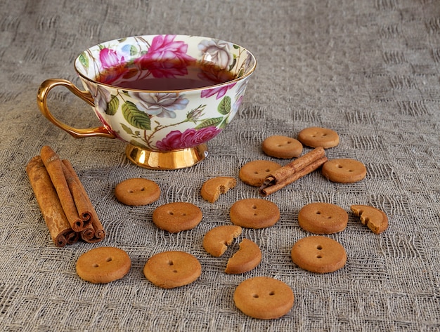 Xícara de chá witn biscoitos e canela na mesa