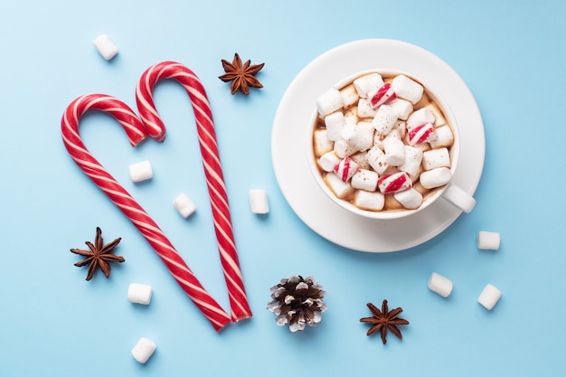 Xícara de chocolate quente com marshmallow cacau em pó e caramelo sobre fundo azul pastel com espaço de cópia. conceito de inverno natal.