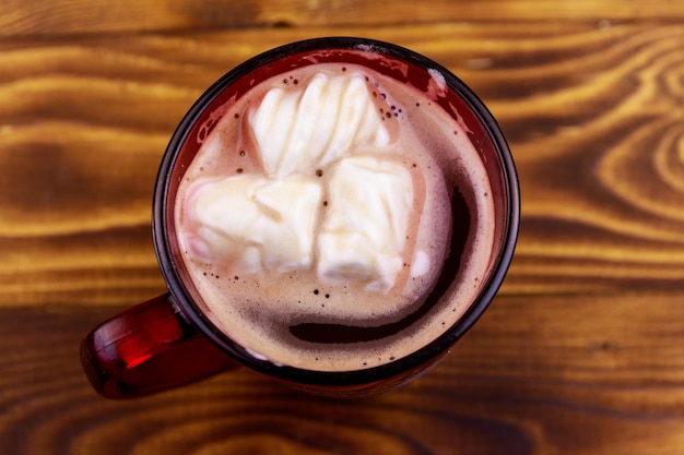 Xícara de chocolate quente com marshmallow derretido na mesa de madeira