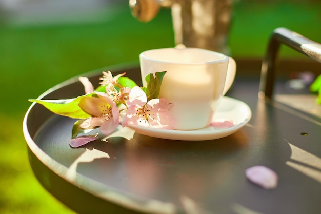 Xícara de flores de café e notebook na pequena mesa preta