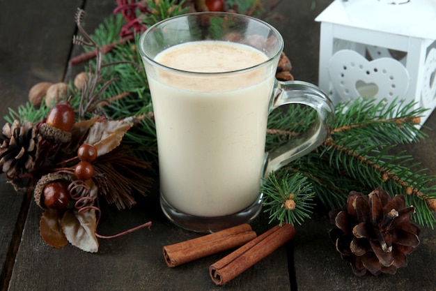 Xícara de gemada com galhos de pinheiro e decorações de Natal em fundo de madeira