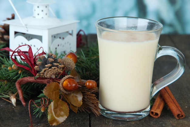 Xícara de gemada com galhos de pinheiro e decorações de Natal na mesa com fundo brilhante