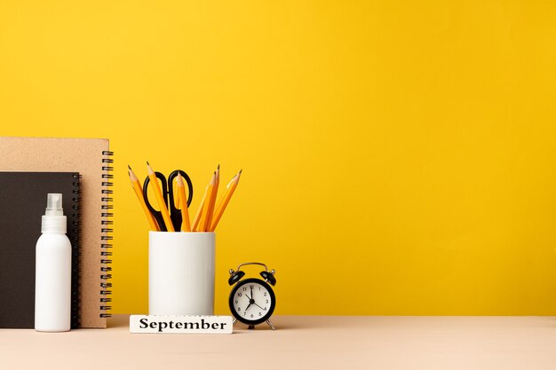 Xícara de lápis e blocos de notas na mesa em amarelo