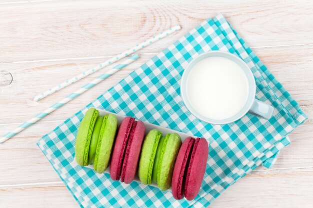 Xícara de leite e macarons na mesa de madeira branca