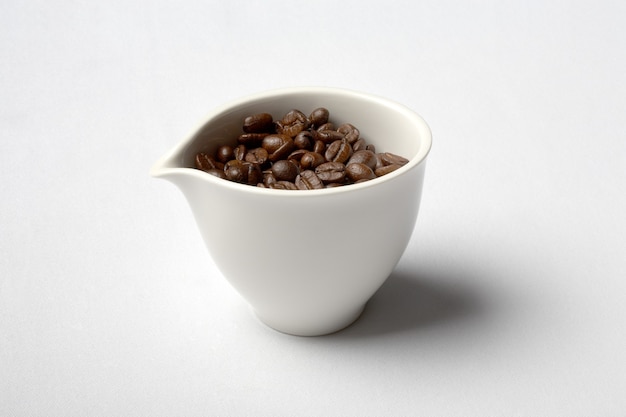 xícara de porcelana branca cheia de grãos de café colombiano