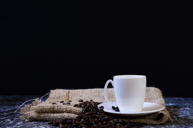 Xícara de porcelana branca do conceito do dia mundial do café com grãos de café