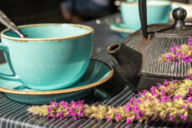 Xícara turquesa de chá quente e um pequeno bule em uma mesa em um café