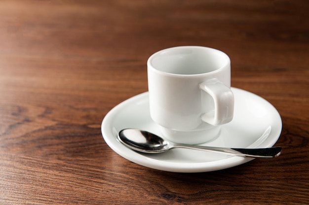 Xícara vazia para café com colher em uma mesa de madeira vista superior e closeup