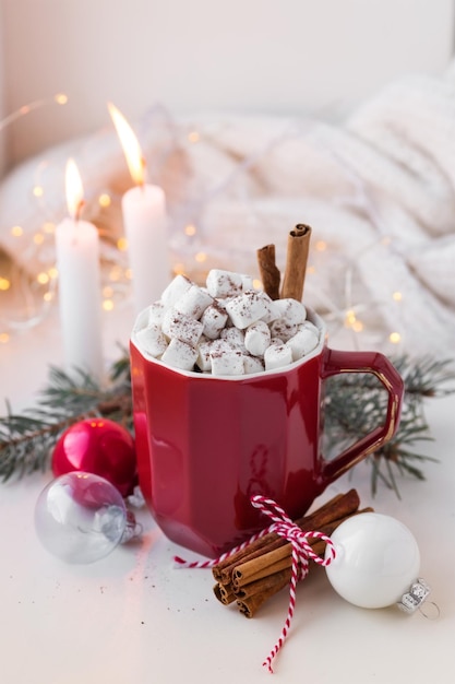 Foto xícara vermelha com cacau e marshmallows decorada com bebida de inverno de paus de canela