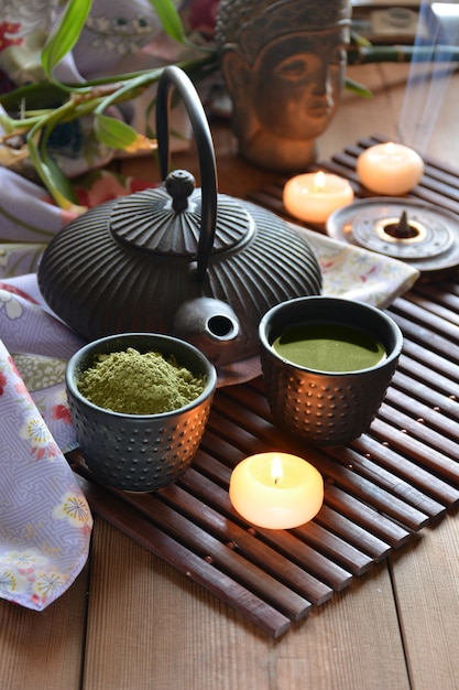 Xícaras cheias de chaleira japonesa de água quente e incenso e velas