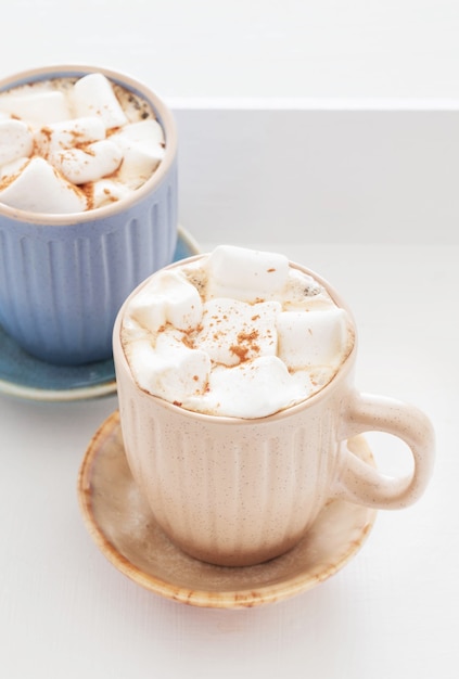 Xícaras de cacau com marshmallows na bandeja de madeira branca