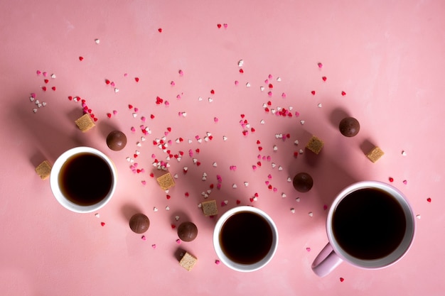 Xícaras de café, chá, chocolate doce de doces em fundo de corações rosa. Conceito mínimo de dia dos namorados 14 de fevereiro. Camada plana, vista de cima, de cima