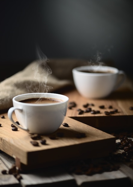 Xícaras de café e grãos de café em uma mesa de madeira