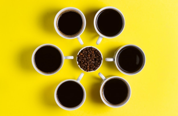 Xícaras de café expresso com grãos de café em fundo amarelo