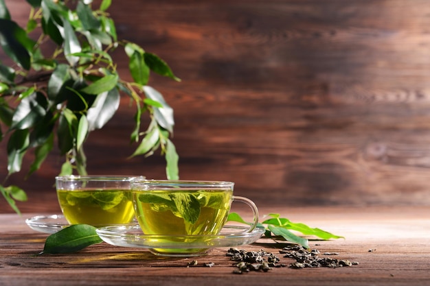 Xícaras de chá verde na mesa sobre fundo de madeira