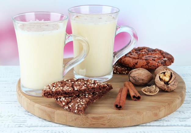 Xícaras de gemada com canela e biscoitos na mesa no fundo brilhante