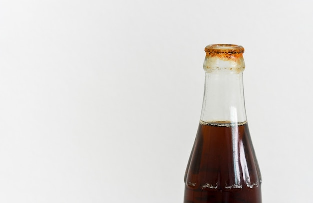 Óxido sucio alrededor de la boca de la botella de vidrio de refresco sobre fondo blanco.