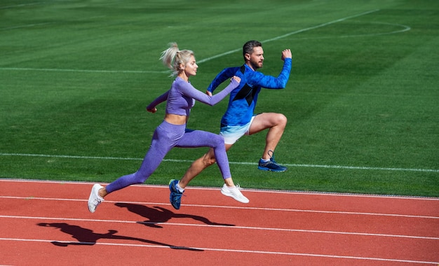 Éxito a cualquier precio pareja de fitness entrenando corredores al aire libre en el desafío de la pista de atletismo y la resistencia de la competencia energía vitalidad en forma deportistas saltando hombre y mujer entrenador deportivo correr