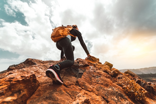 Éxito mujer excursionista senderismo en el pico de la montaña del amanecer - Mujer joven con mochila subir a la cima de la montaña. Concepto de destino de viaje de descubrimiento