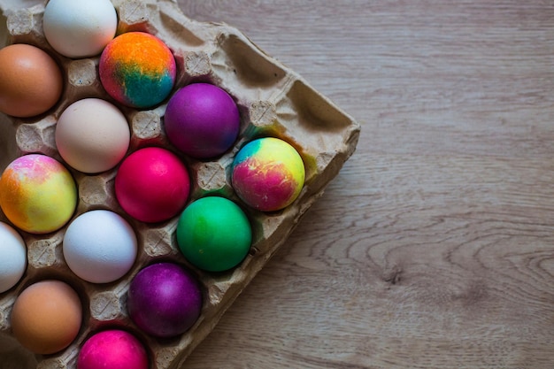 XMehrfarbig bemalte Ostereier liegen in einer Kiste auf einem Holztisch Ostern Frühling Bemalte Eier