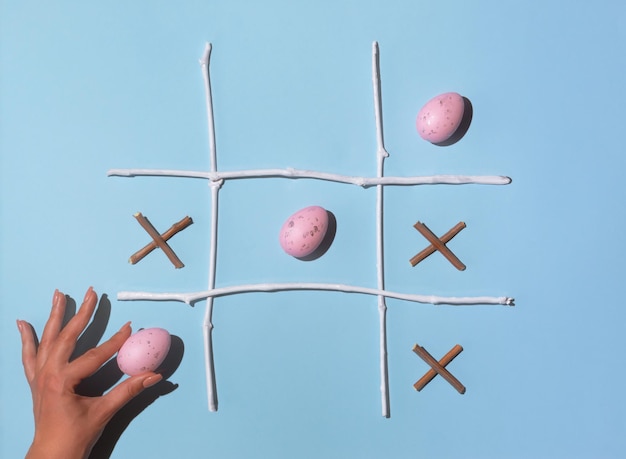 XO-Spiel aus Ostereizweigen und Frauenhand Kreative Tic-Tac-Toe-Spielidee