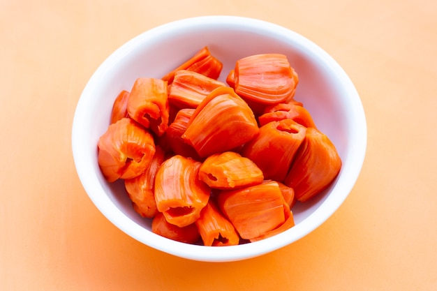 Yaca roja madura en mesa naranja.