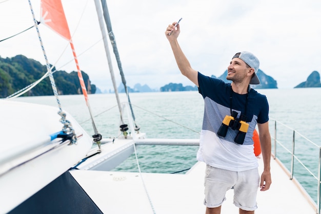 Yacht des jungen Mannes macht ein selfie am Telefon. Reisen und aktives Leben. Luxusurlaub