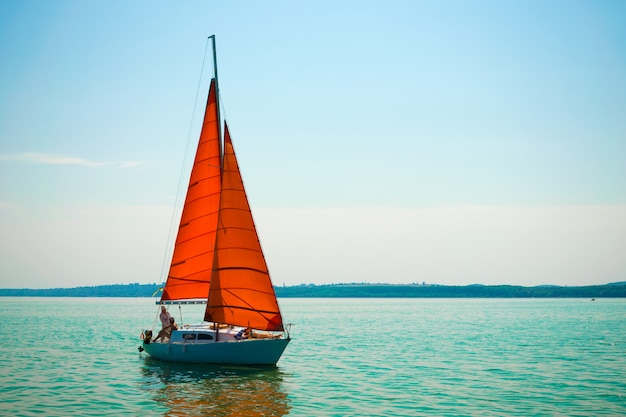 Yacht mit roten Scharlachroten Segeln auf dem See