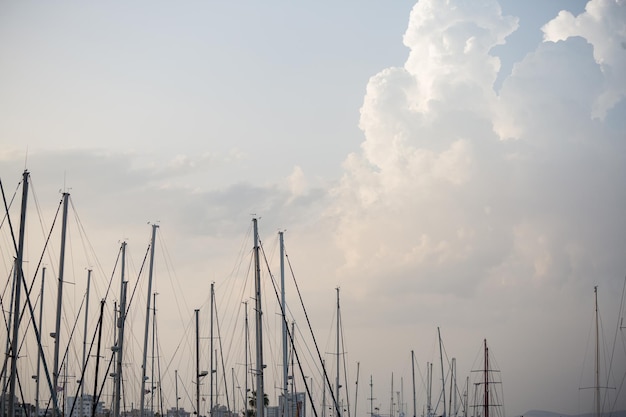 Yachten Masten Tops unter Larnaca's blauer Himmel mit flauschigen Wolken Himmel und Stadt Hintergrund