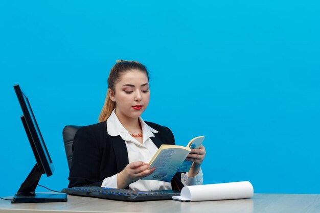 Yahoo se le dice a una mujer de negocios sentada en el escritorio y leyendo un libro