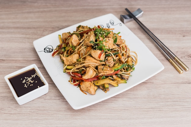 Yakisoba con salsa de soja sobre una mesa de madera.