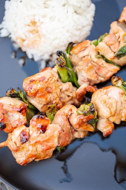 Yakitori de pollo con arroz blanco en un plato.