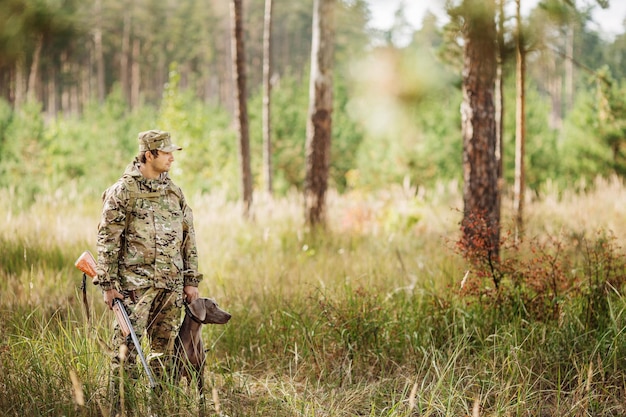 Yang Hunter con rifle y perro en el bosque