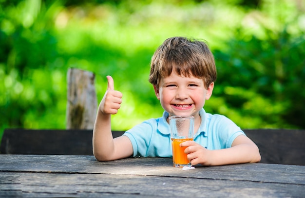 Yang niño pequeño y lindo en la foto con un vaso de jugo.