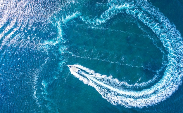 Un yate de alta velocidad maniobra en la superficie del agua. Vacaciones en el mar o en el océano, alquiler de embarcaciones marítimas. Deportes acuáticos.