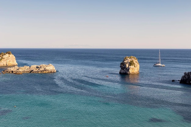 Yate blanco amarrado en mar abierto cerca de la costa y la ciudad de Parga en un día soleado de verano región de Epiro Grecia