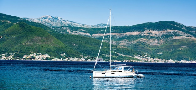 Yate blanco en el mar adriático montenegro con montañas escénicas y bosque en el fondo barco de lujo en ...