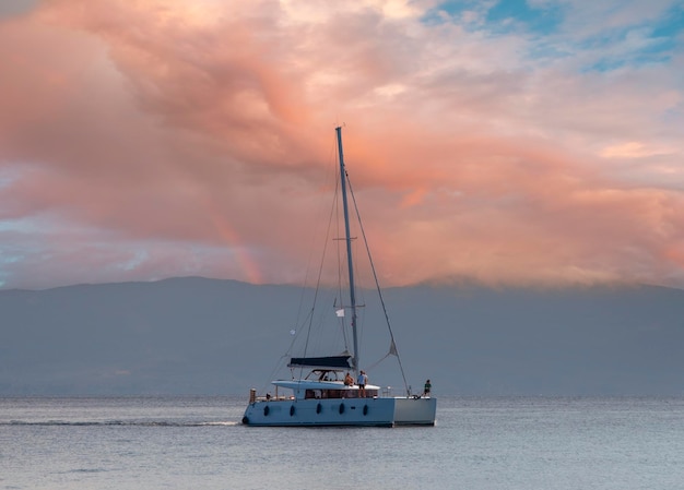 Yate-catamarán en un día nublado en el tranquilo Mar Egeo en la isla de Evia, Grecia al atardecer