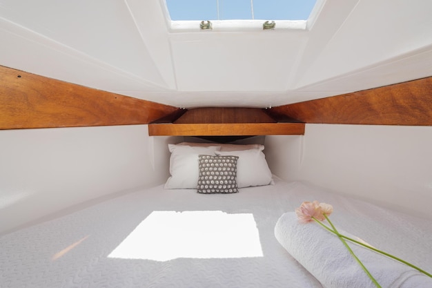 Yate cómodo de lujo brillante en el interior con molduras de madera con sábanas de felpa blanca, almohadas, flores y