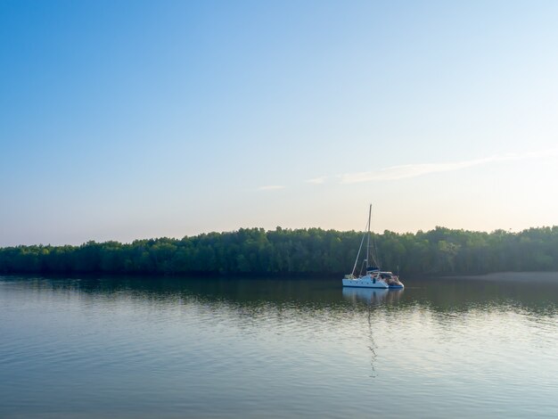 Yate en el lago azul en bosque verde y cielo azul