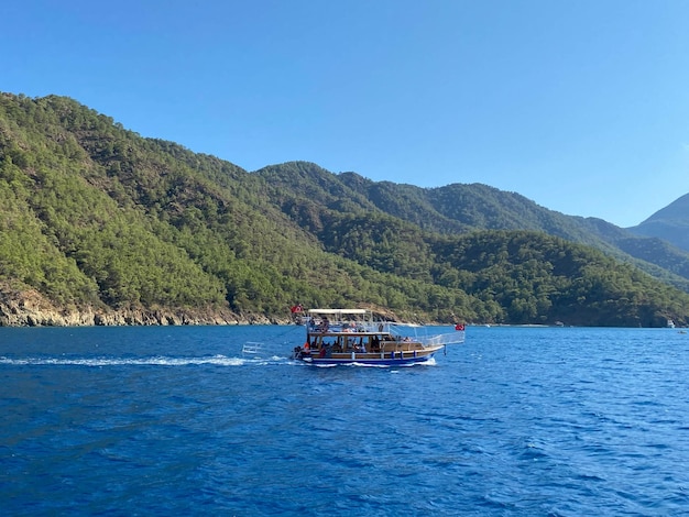 Yate en medio del mar contra el fondo de montañas con nubes azules